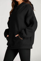 Black oversized fleece-lined hoodie with front pocket and relaxed fit for cozy travel wear