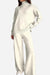 Woman wearing an off-white knitted turtleneck sweater and wide-leg pants two-piece set