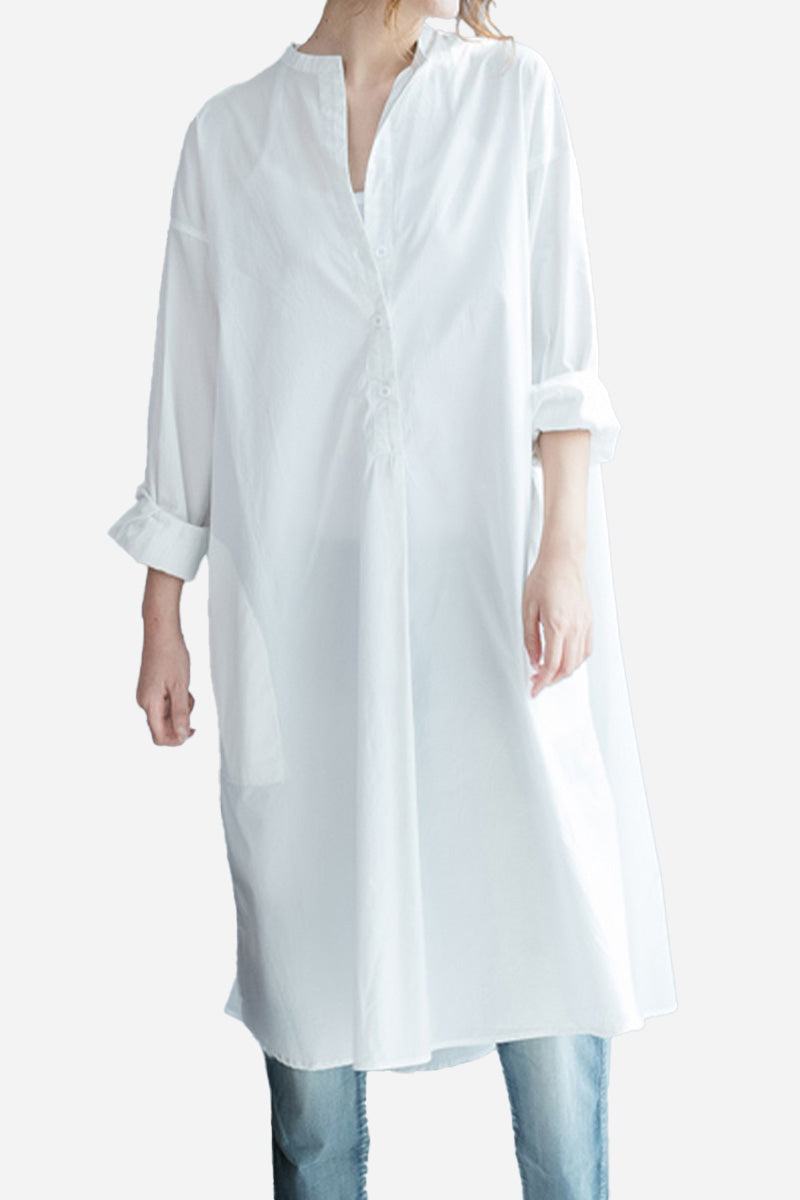 White pure cotton long shirt with oversized fit and button-front design, styled with rolled-up sleeves and paired with jeans.