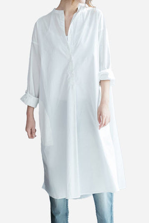 White pure cotton long shirt with oversized fit and button-front design, styled with rolled-up sleeves and paired with jeans.