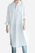 White pure cotton long shirt with oversized fit and button-front design, styled with rolled-up sleeves and paired with jeans.