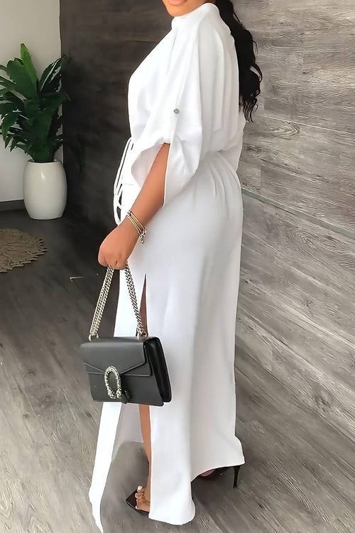White All-Day Drape Dress with adjustable waist tie and front slit, styled with a black handbag and heels.