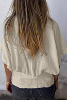 Back view of a woman wearing a beige 100% pure linen short-sleeve blouse with a relaxed fit and natural wrinkles.