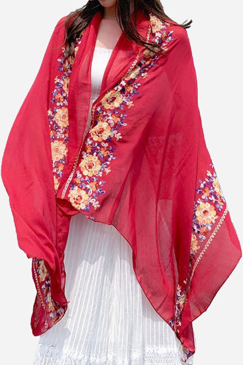 Lightweight red embroidered travel shawl with floral details draped over a white dress