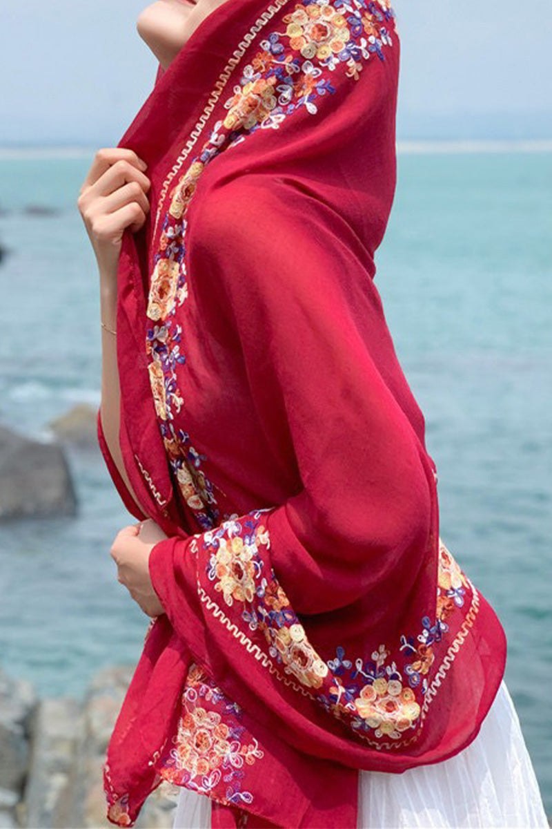 Red embroidered travel-must shawl with floral details worn as a head wrap by the seaside