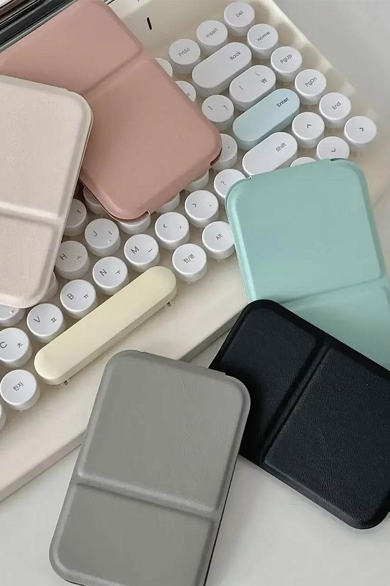 Compact Travel Pocket Mirror with durable PU leather case in multiple colors placed on a white keyboard