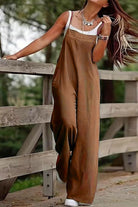 Woman wearing brown wide-leg cotton blend comfort jumpsuit outdoors near wooden fence