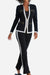 Woman wearing a black sleek contrast zip two-piece outfit with white trim and gold zipper details.