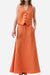 Woman wearing a sunset orange cotton-linen blend sleeveless vest and flowing skirt two-piece set.