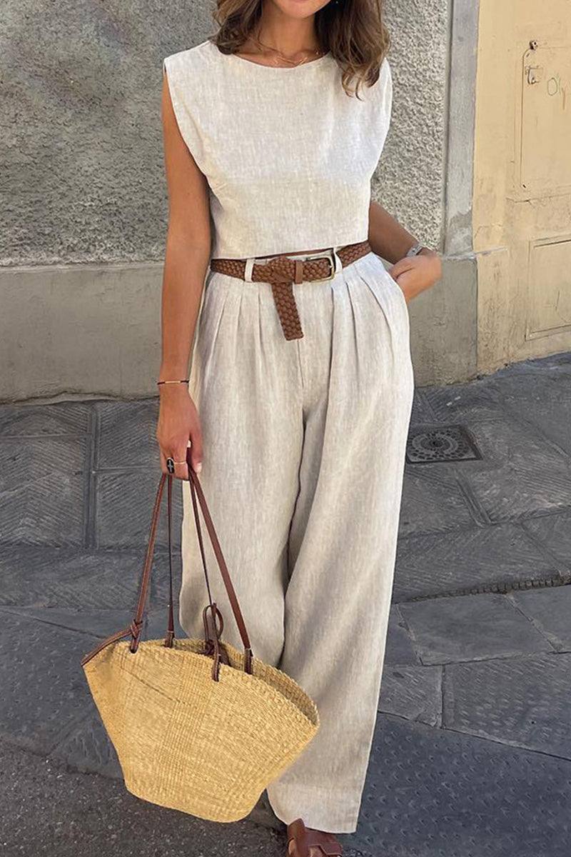 Woman wearing cotton-linen blend sleeveless crop top and wide-leg pants summer outfit with brown belt and straw handbag