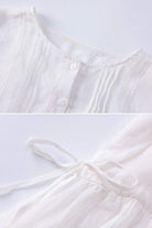 Close-up of white 100% linen coastal shift dress showing button front and waist tie detail