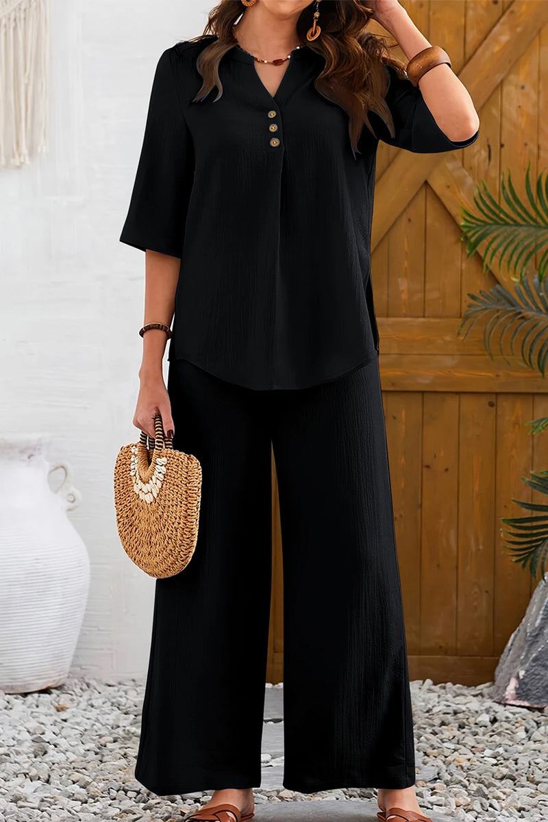 Woman wearing black wrinkle-free wide leg pants and button-front top set with three-quarter sleeves holding a woven handbag