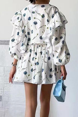 Back view of woman wearing Sweet Countryside 100% cotton ruffled two-piece set with floral print and puff sleeves, holding blue handbag