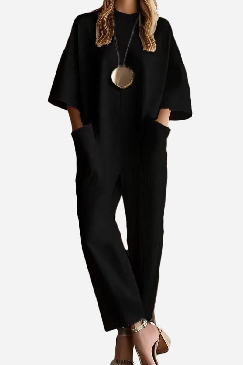 Black serene minimalist pocket jumpsuit with relaxed fit, short sleeves, and deep side pockets.