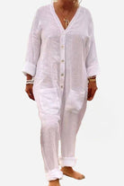 White relaxed jumpsuit with button-front, deep V neckline, and rolled sleeves for casual summer wear.