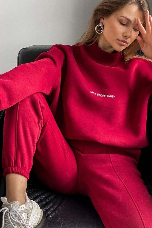 woman wearing red Storm Sweater Mock Neck athleisure set with jogger pants and sneakers sitting on black chair