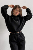 Woman wearing black Storm Sweater Mock Neck athleisure set with relaxed fit and adjustable waist
