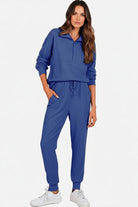 Woman wearing a blue unisex half-zip pullover and sweatpants set with a stand collar and casual fit