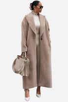 Woman wearing oversized teddy coat in beige with longline silhouette and oversized lapels, styled with matching outfit and handbag