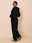 woman wearing black waffle-knit two-piece hoodie and pants set with relaxed fit and wide-leg pants