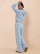 woman wearing light blue waffle-knit two-piece lounge set with hoodie and wide-leg pants, back view