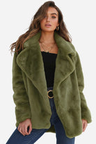 Woman wearing green open front oversized faux fur jacket with draped shawl collar and mid-hip length