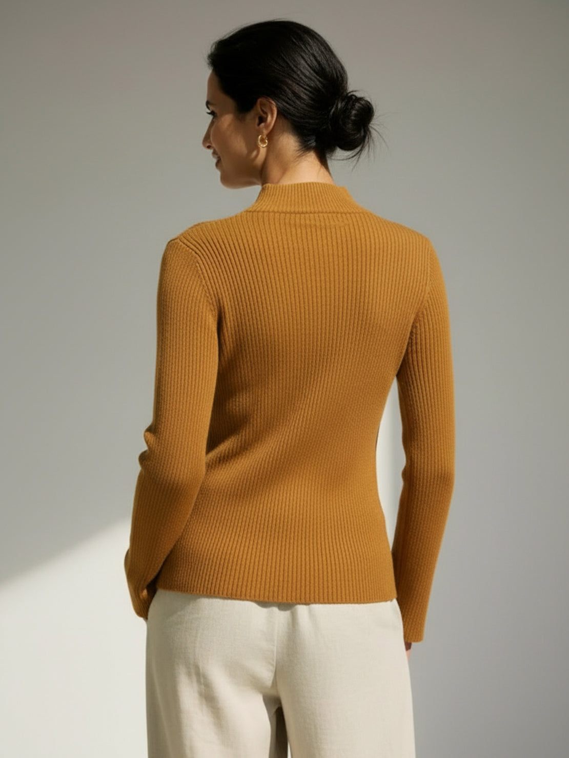 woman wearing slim fit asymmetric wrap ribbed knit top with diagonal button detail and flared cuffs