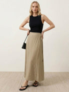 Woman wearing asymmetrical wrap maxi skirt with side tie and flowing asymmetric hem.