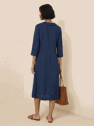 Woman wearing a navy linen-look midi dress with 3/4 sleeves and side pockets standing outdoors