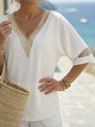 Mature woman wearing a lightweight linen top with V-neck, short sleeves, and button details in light khaki