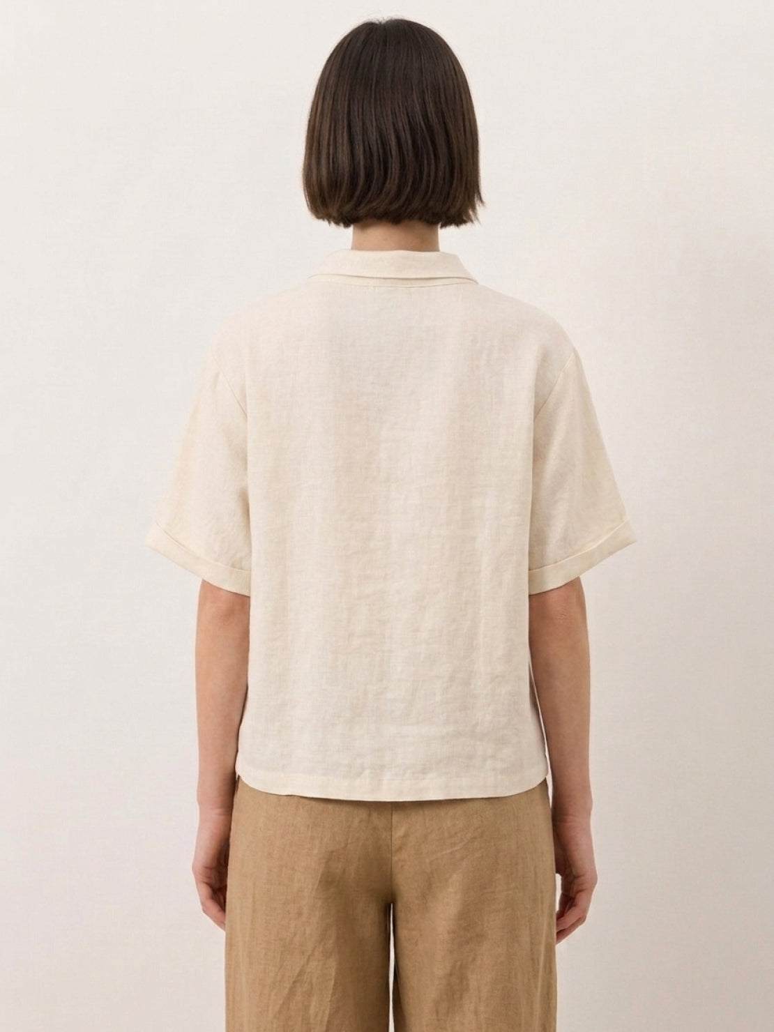 Woman wearing 100% linen top with relaxed fit and asymmetric button detail