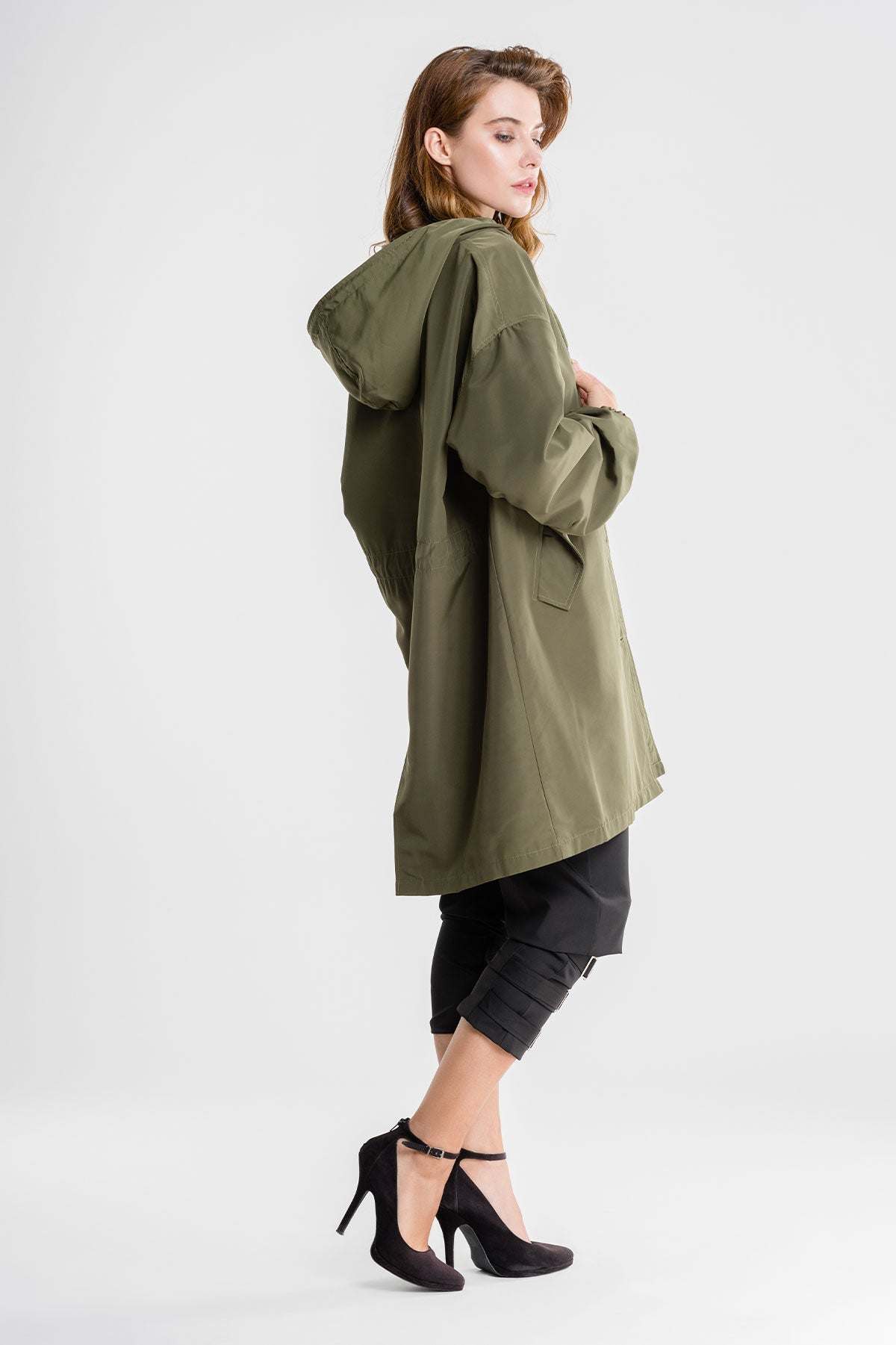 Woman wearing olive green water resistant oversized windbreaker with hood and pockets