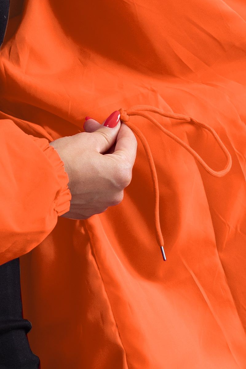 Close-up of orange water resistant oversized windbreaker showing adjustable drawstring detail