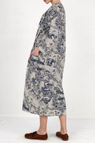 Side view of a woman wearing a Japanese Porcelain Print midi dress with 3/4 sleeves and oversized pockets in cozy blue patterned fabric