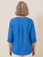 White pure linen age-defying shirt with button detail on hanger against white background