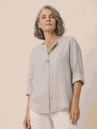 Woman wearing a pure linen age-defying button detail shirt in soft beige, showcasing breathable and elegant fabric design