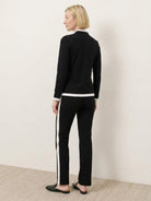 Woman wearing sleek contrast zip two-piece outfit with black and white accents standing against white background
