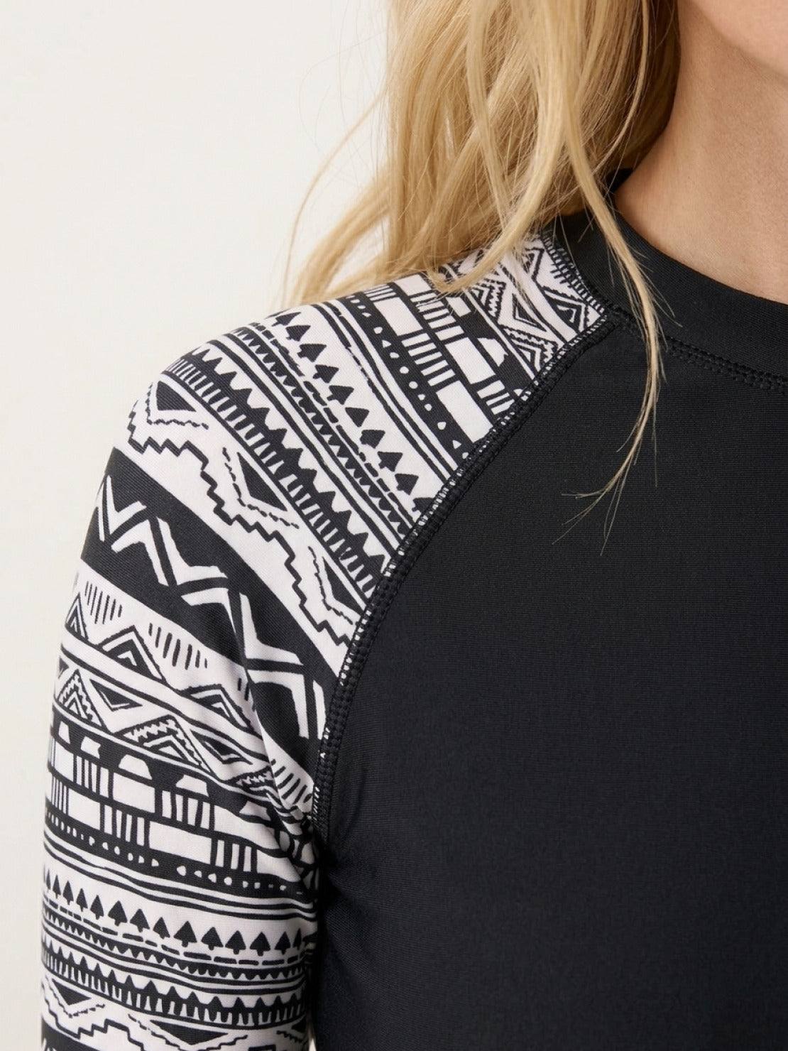 Woman wearing swim shorts rash guard set with long raglan sleeves and matching boyshort bottoms on beach
