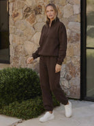 Woman wearing a stylish cotton-blended two-piece tracksuit with high collar and deep zipper, showcasing casual comfort and polished athleisure style.