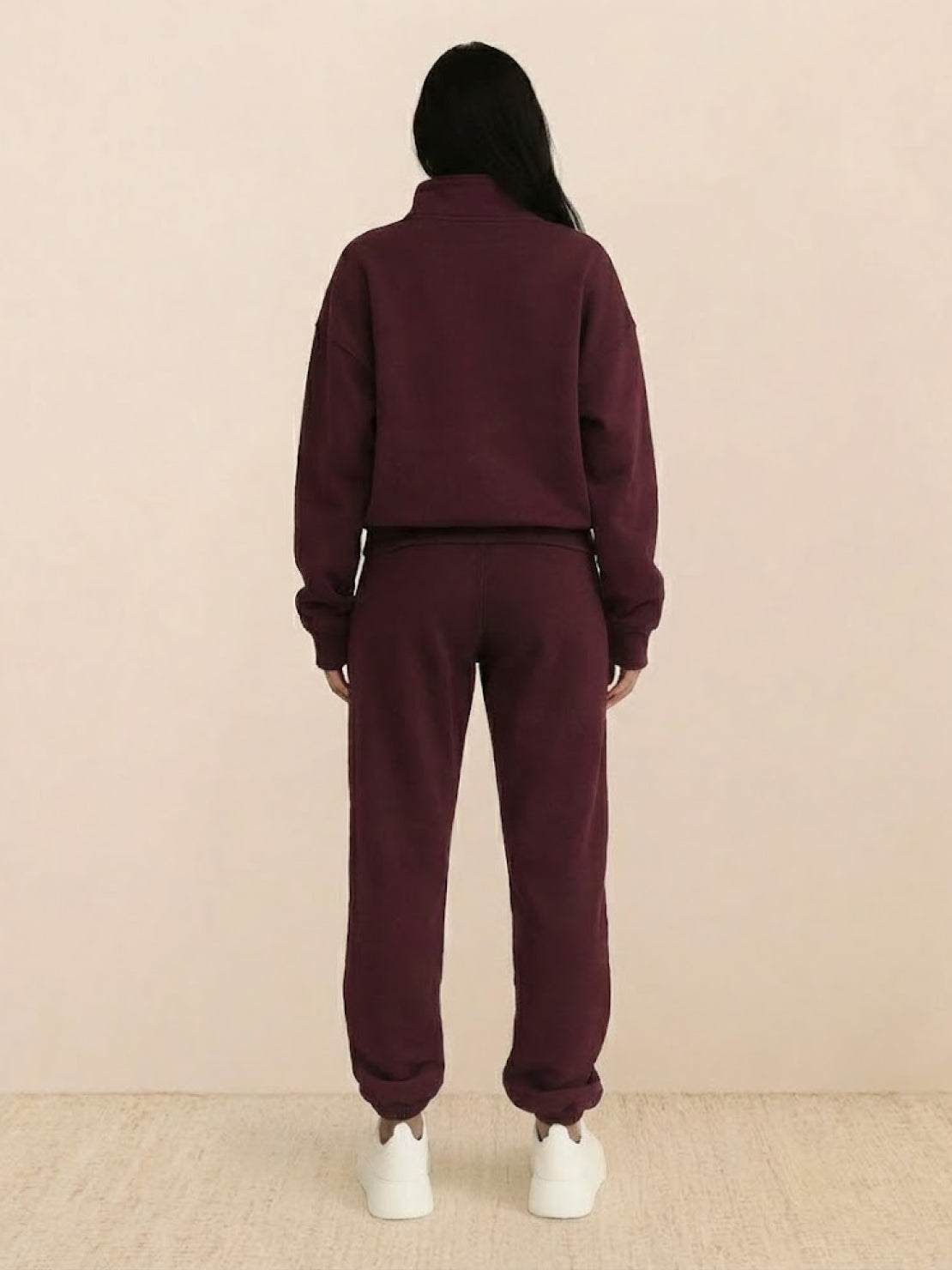 Woman wearing cotton-blended two-piece tracksuit with high collar and zipper, styled for casual athleisure look
