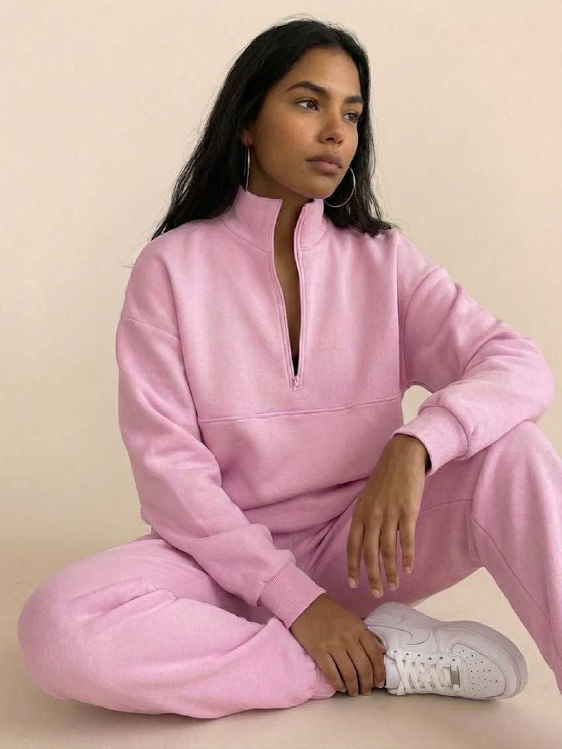 Woman modeling a cotton-blended two-piece tracksuit with high collar and zipper in a casual athleisure style