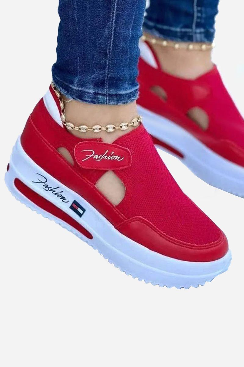 Red breathable wedge sneakers with white sole and velcro closure worn with jeans and ankle bracelet