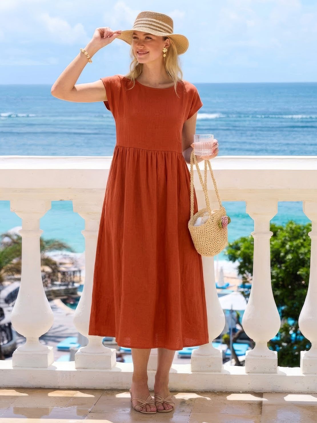 Woman wearing a capped-sleeve voluminous pleated midi dress with pockets and flowing skirt