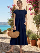 Woman wearing capped-sleeve voluminous pleated midi dress with flowy skirt and pockets