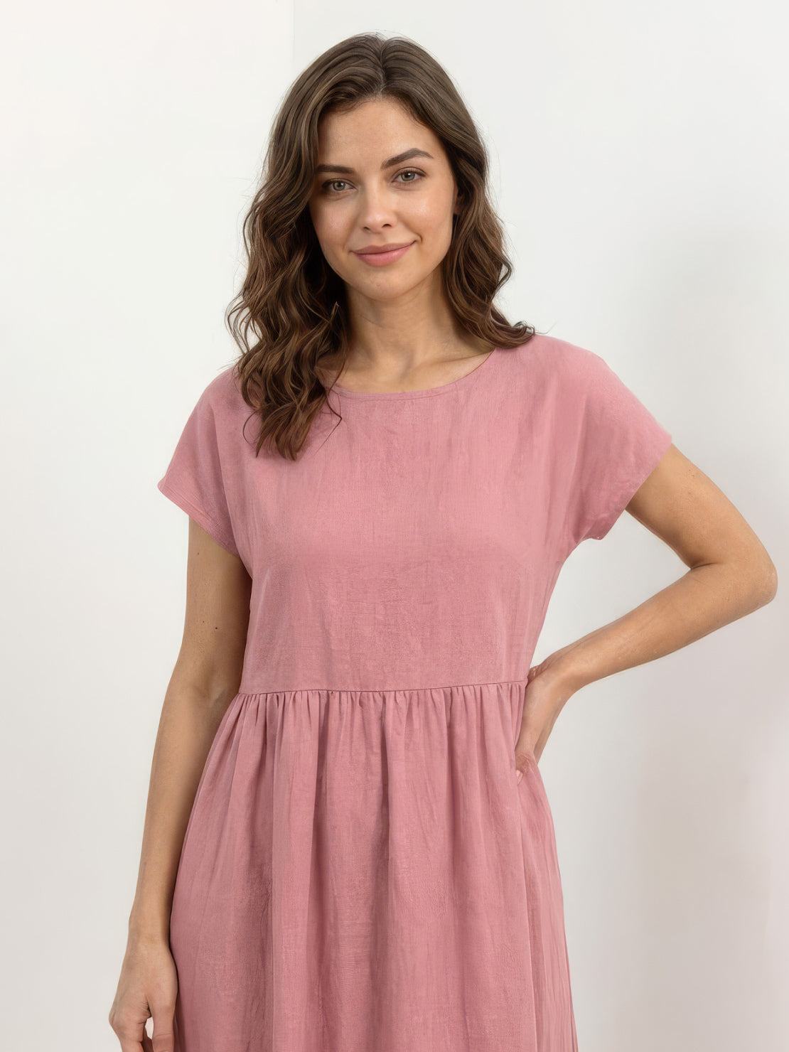 Woman wearing capped-sleeve voluminous pleated midi dress with pockets and flowing skirt