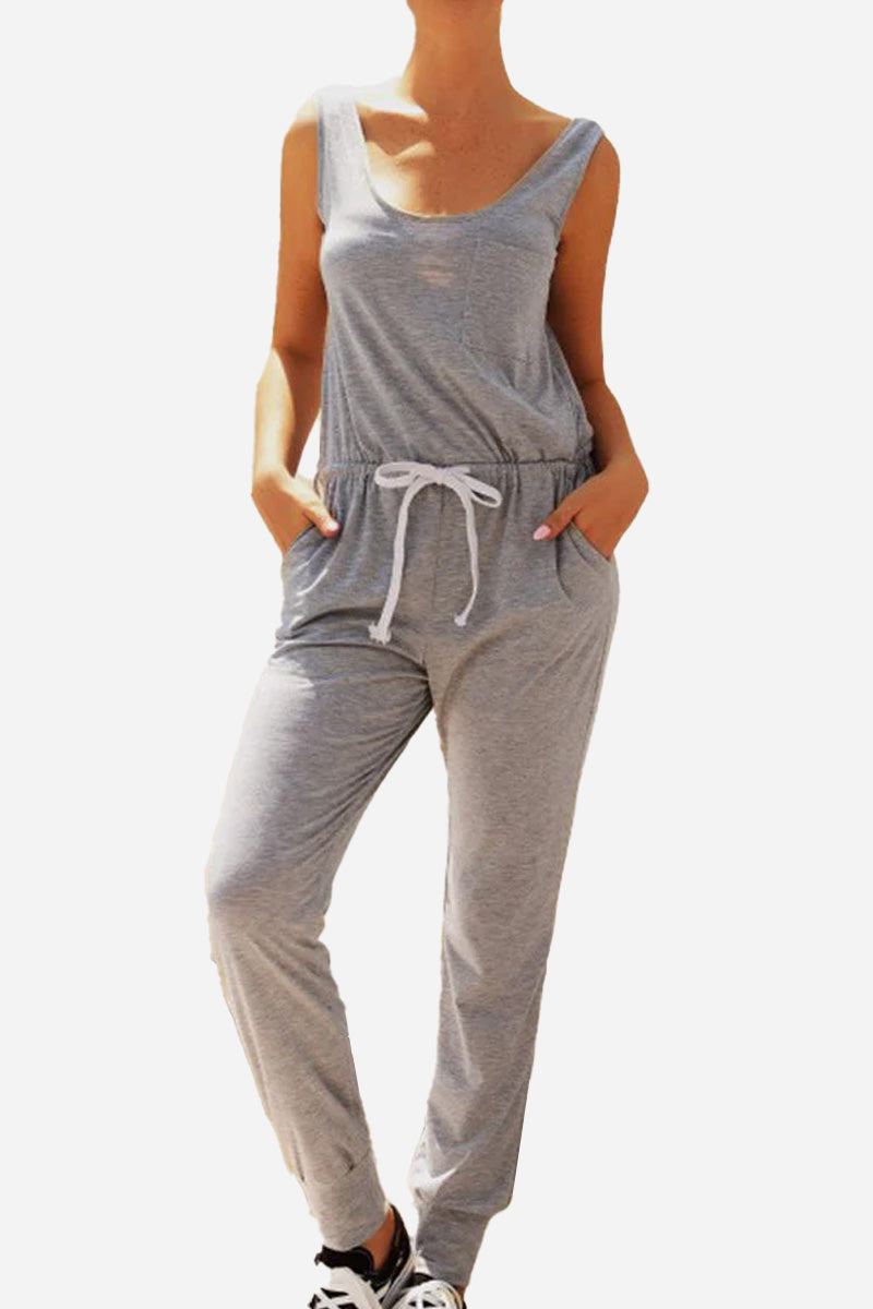 Woman wearing a grey comfy sleeveless vest pocket jumpsuit with elastic waistband and drawstring.