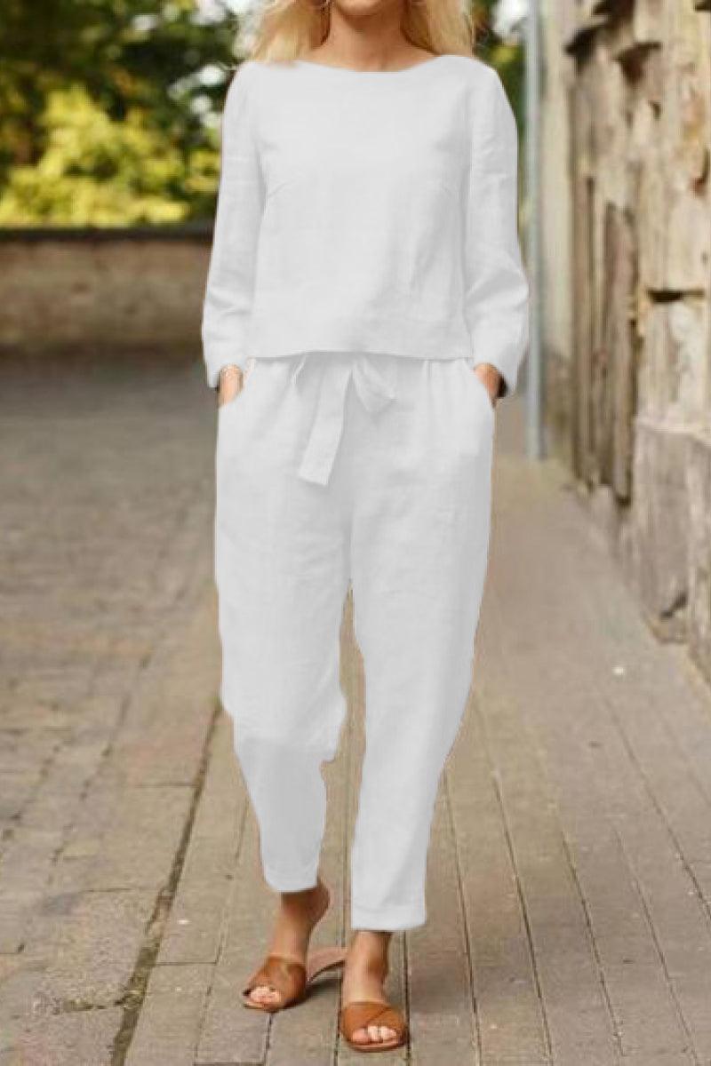 Woman wearing white cotton-linen monochrome relaxed longline top and wide-leg pants with brown sandals outdoors