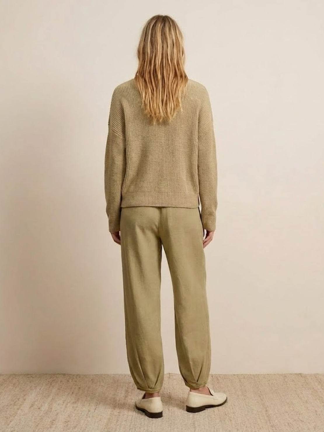 Back view of relaxed sweater top and trouser set in neutral tones embodying European minimalism style