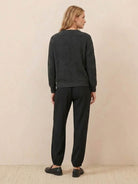 woman wearing European minimalism relaxed black sweater top and trouser set viewed from back