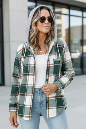 Woman wearing green and white Highland Plaid Shacket with hood, fleece lining, and button front closure.